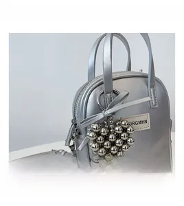 Detail of silver metallic phone bag with heart-shaped bead charm and URGMHN brand label