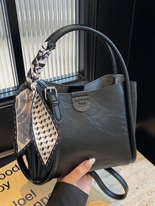 Minimalist black bucket bag with patterned scarf handle and adjustable strap for women
