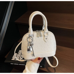 Dettaglio borsa a conchiglia in pelle di struzzo bianca con finiture in argento e lucchetto