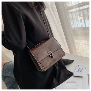 Detailed close-up of brown vintage leather bag showing metal chain strap and square clasp