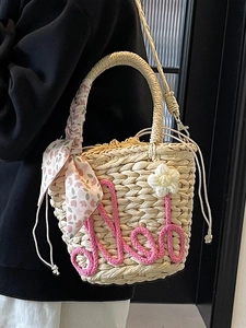 Beige woven straw bucket bag with pink floral scarf handle and crochet flower charm