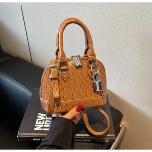 Dettaglio borsa a conchiglia in pelle di struzzo marrone con hardware argento e lucchetto