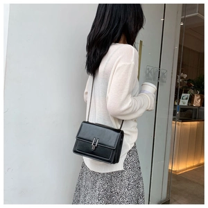 Detail of black retro chain bag with white contrast stitching and silver metal buckle closure