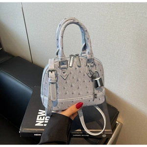Dettaglio borsa viola con texture struzzo, doppia cerniera e ciondolo lucchetto in metallo