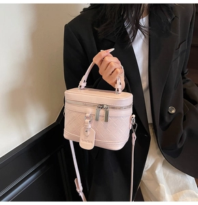 Pink box bag with quilted pattern, top handle and thin strap on a blazer model
