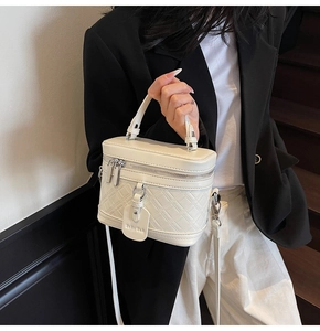 Close-up of cream quilted leather box bag featuring a checkered pattern and dual zippers