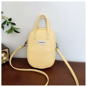 Detailed macro view of the yellow leather crossbody bag on a wooden table surface