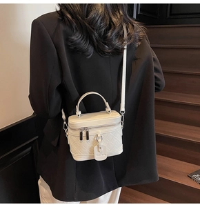 Detailed back view of white quilted crossbody box bag on a black blazer jacket