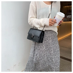 Fashionable black matte leather crossbody bag with silver buckle worn by a female model