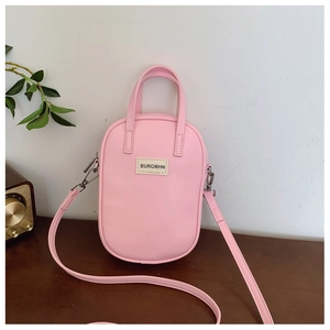 Pink oval crossbody bag with woven BURGMHN label on a smooth synthetic leather surface
