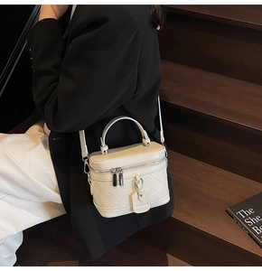 Detail of ivory box bag with quilted pattern and elegant handle in chic setting