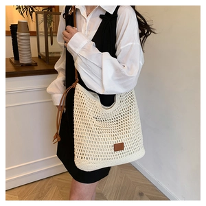 Detail view of hollow crochet tote bag with brown faux leather patch and shoulder strap