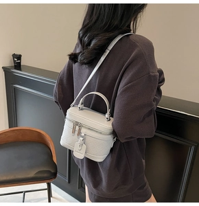 Detailed side view of a white quilted box bag with dual zippers and adjustable strap