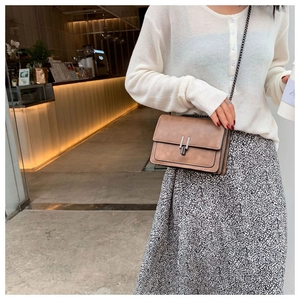 Close-up of brown retro leather crossbody bag with metal buckles and chain strap