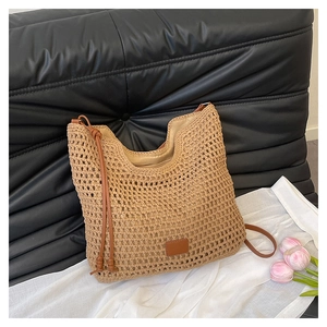 Detail of hollow woven tote bag with brown faux leather strap and minimalist label