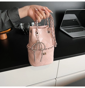 Detailansicht der rosa gesteppten Beuteltasche mit Kette und Schleifenanhänger