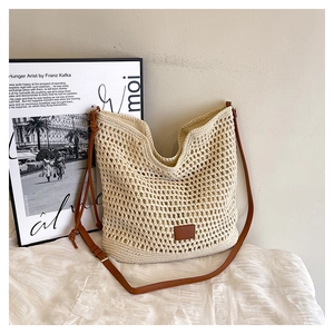 Detail view of beige hollow crochet tote bag with adjustable brown leather strap and inner lining