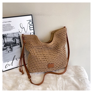 Detail of khaki hollow woven hobo bag with brown leather strap and tassel detail