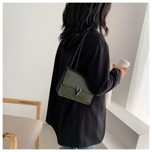 Detail of dark green square chain bag with white stitching and silver buckle