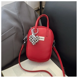 Close-up of a red leather phone bag with a silver heart charm on an open book