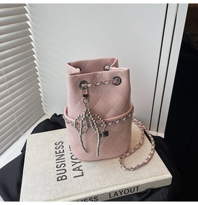 Detail einer rosa gesteppten Beuteltasche mit silberner Kette und Schleifenanhänger