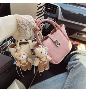 Detailed macro view of litchi texture leather bucket bags with plush bear charms