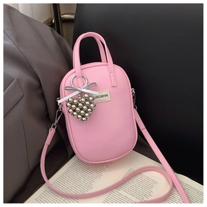 Detailed shot of pink capsule crossbody bag with silver heart charm and silk bow detail