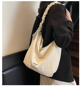 Detail view of cream tote bag featuring ruffled shoulder strap and tennis racket charm