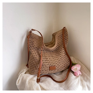 Detailed close-up of khaki hollow woven tote bag with brown leather straps on white fabric