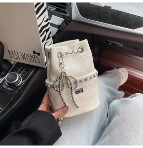 Nahaufnahme der cremefarbenen Stepptasche mit Silberkette und Schleife im Auto-Innenraum
