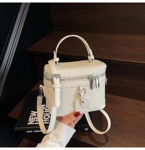 Detail of white quilted box bag with silver hardware and detachable crossbody strap