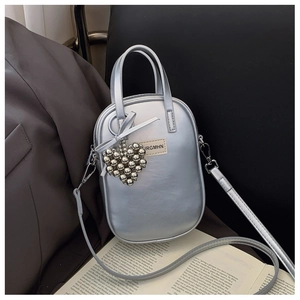 Detailed view of oval silver metallic handbag with heart charm and detachable shoulder strap