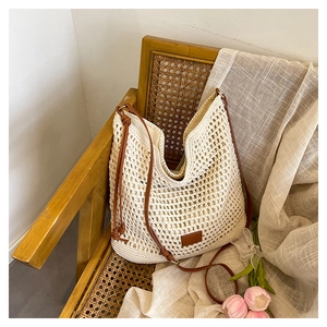 Macro detail of beige crochet hobo bag with brown leather strap on vintage chair