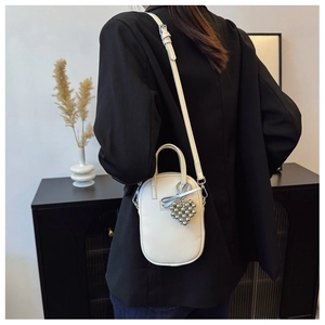 Detail view of cream crossbody phone bag with heart pendant and adjustable strap