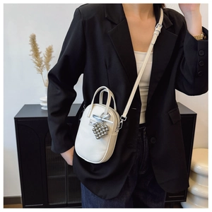Vertical white crossbody bag with heart charm and blue bow shown on model