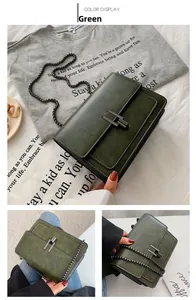 Detail of dark green vintage textured crossbody bag with metal H-buckle and chain strap