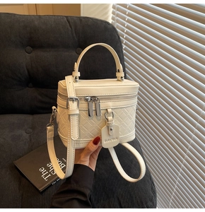 Detail of cream quilted box bag with dual zippers and detachable shoulder strap