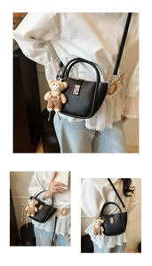 Close-up of black lychee grain leather bucket bag with silver buckle and teddy bear charm
