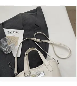 Detail view of cream white bucket bag with pearl lace charm and adjustable shoulder strap