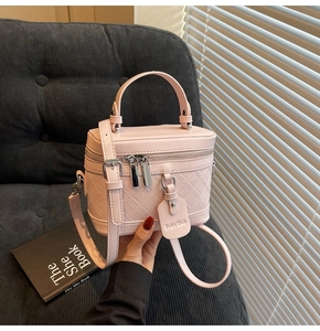 Detail of pink quilted leather vanity bag with metal zippers and branding tag