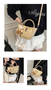 Detail view of cream lychee leather bucket bag with silver lock and teddy bear charm