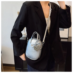 Silver mini crossbody phone bag with bow and heart charms shown on a model