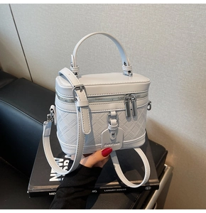 Detailed macro view of light grey quilted vanity case bag with metal zipper and top handle