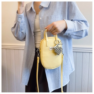 Detail of lemon yellow mini crossbody bag with heart bead charm and brand logo label