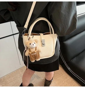 Detail of cream white litchi pattern bucket bag with silver lock and teddy bear charm