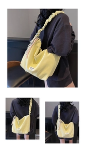 Detail view of bright yellow tote bag featuring ruffled strap and woven decorative charm