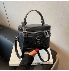 Detail of black quilted box bag with silver metal zippers and adjustable leather strap