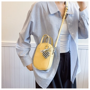 Detailed close-up of yellow mini crossbody bag with silver heart bead charm for women