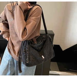 Détail du sac cabas en jean gris délavé avec fermeture à cordon et étiquette rouge