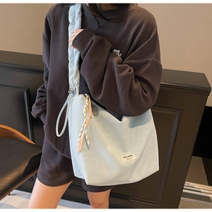 Detail of light blue tote bag with ruched wide strap and colorful knot charm accessory